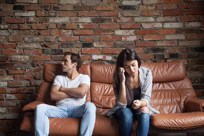 Frustrated upset couple after quarrel sitting on sofa at home